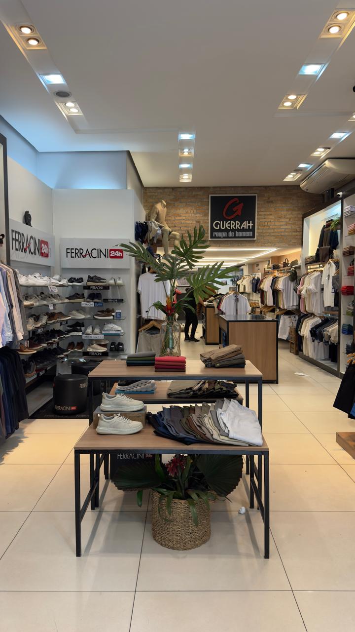 Interior da loja com araras de camisas e mesas de produtos